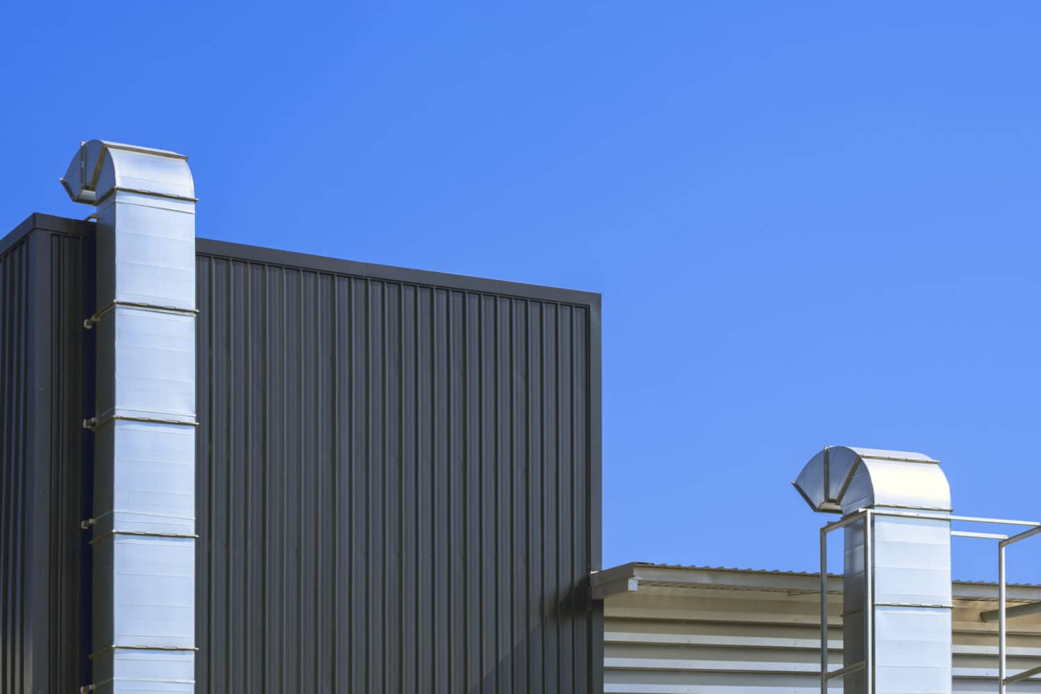 two air ventilation ducts outside modern industrial building against blue clear sky background scaled